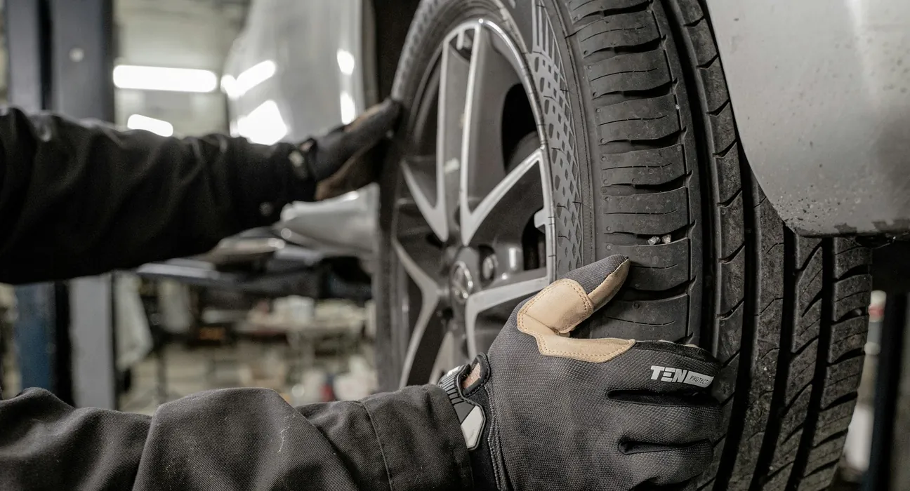 mechanic inspecting a wheel and tire for worn wheel bearings